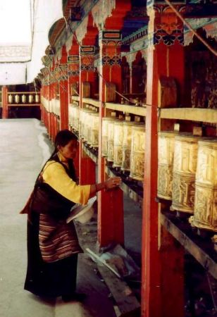 Buddhists don’t pray to God, but believe they can earn merit by turning a prayer wheel as this woman is doing, while reciting the mantra written on it.